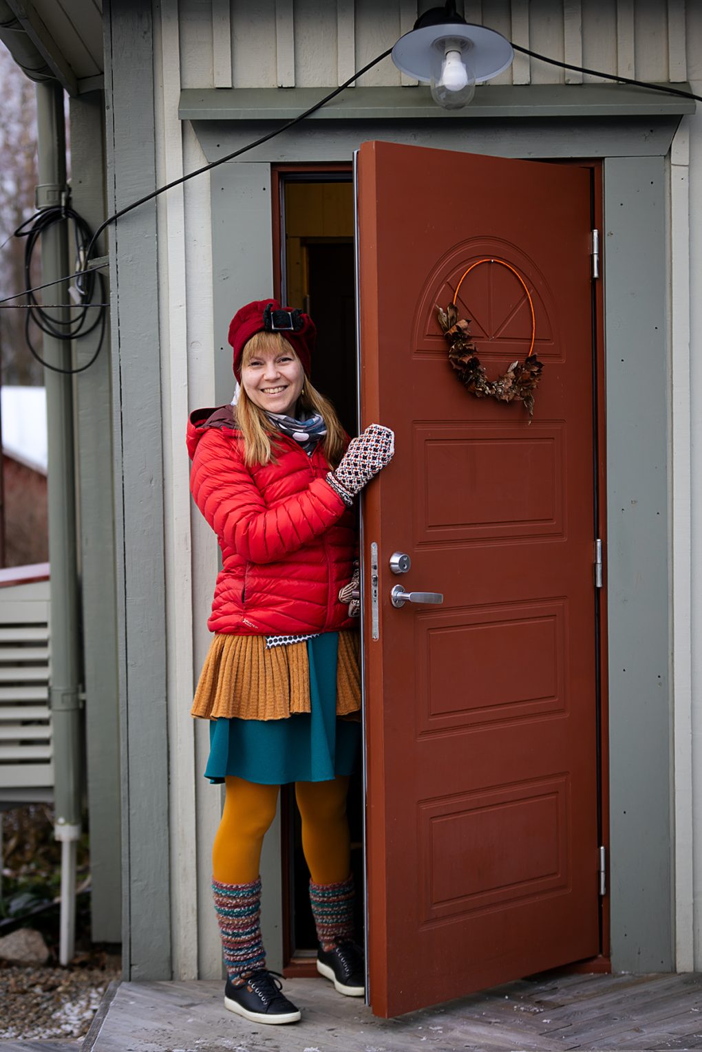 Johanna seisoo talonsa ulko-ovella ja hymyilee kameralle