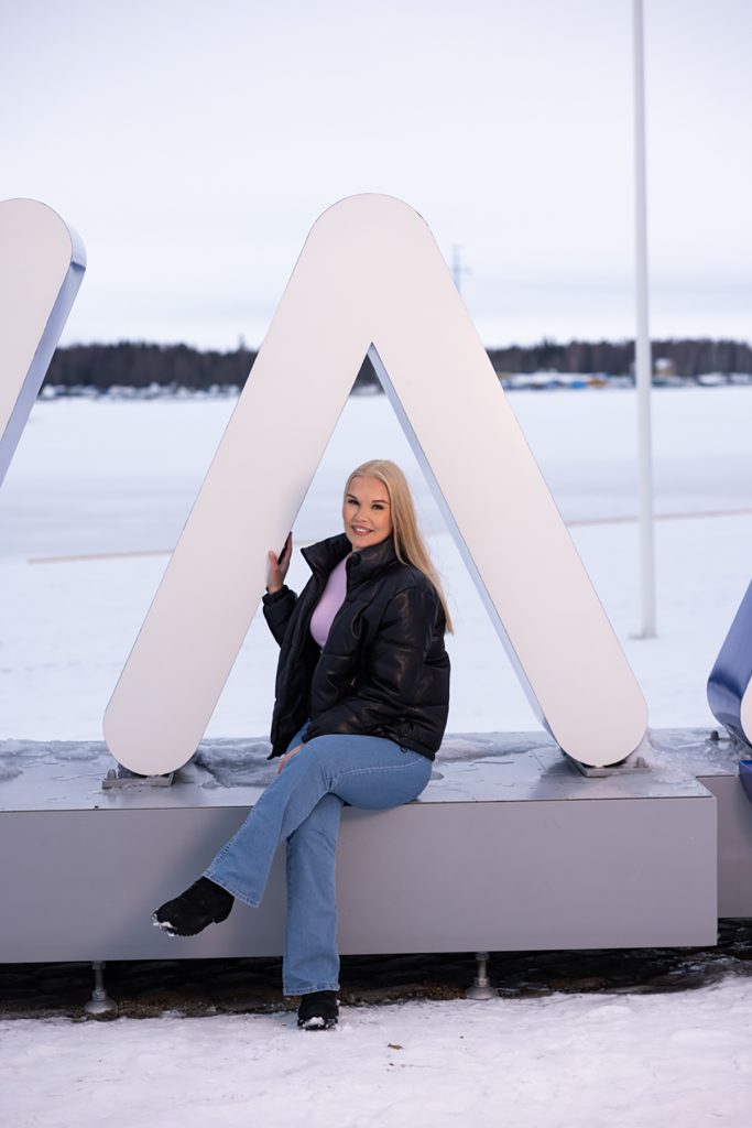 Riikka Könönen istuu Vaasan sisäsatamassa Vaasa-kyltin reunalla