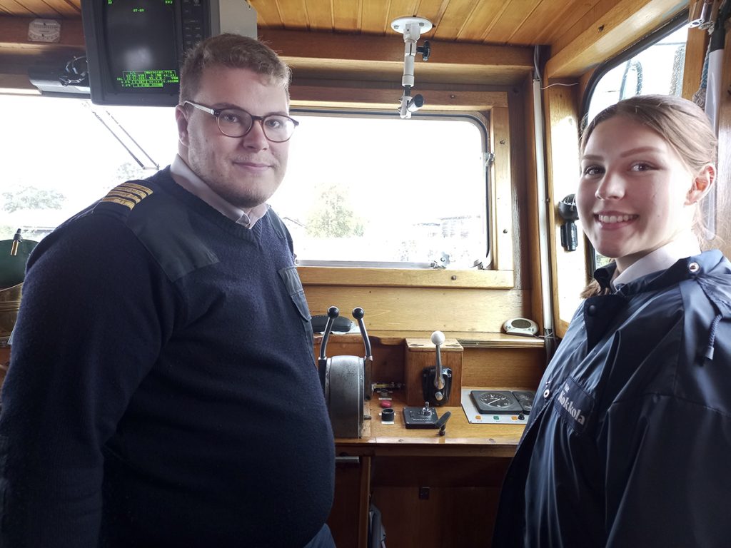 Teemu Mäkelä ja Anni Räisä seisovat M/S Jenny -aluksen ohjaamossa