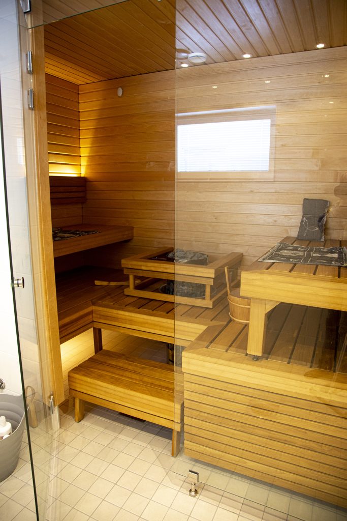 Saunan lasinen ovi on raolla ja sauna näkyy oven takaa